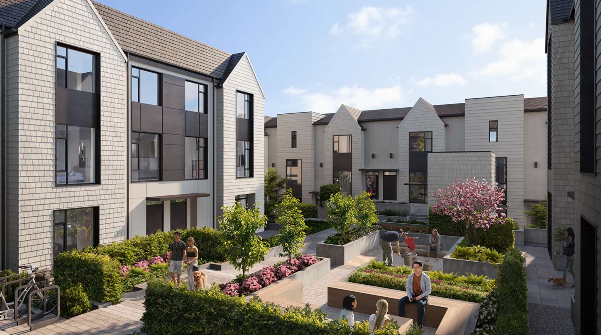 Whitford – A ground-level view of a modern townhome community surrounding a central landscaped courtyard with stone pavers, wooden benches, and raised planters filled with flowers and small trees. Residents are depicted enjoying the bright, daytime outdoor space surrounded by multi-story residential buildings with light siding and large windows.