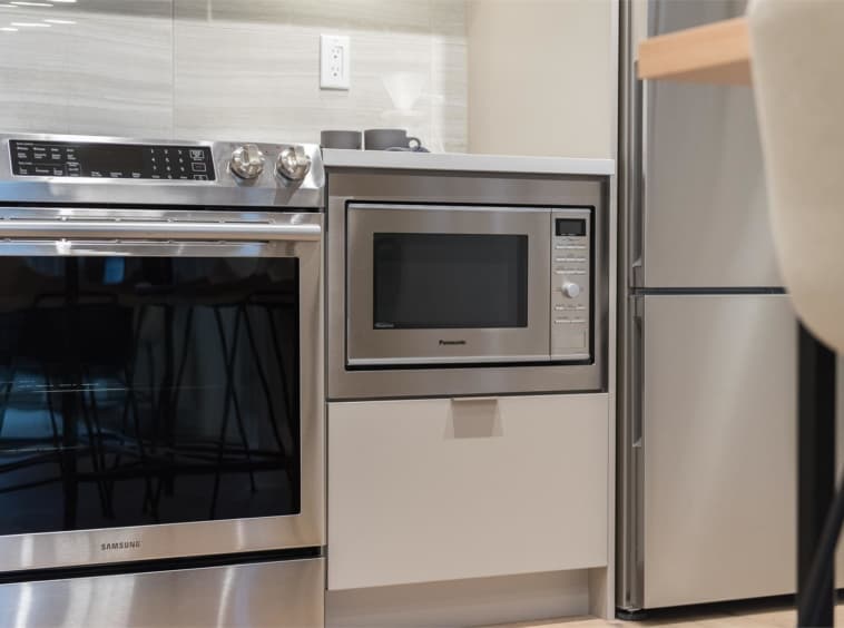 Crescent Court – Close-up of stainless steel kitchen appliances including a Samsung oven range, built-in microwave, and refrigerator.