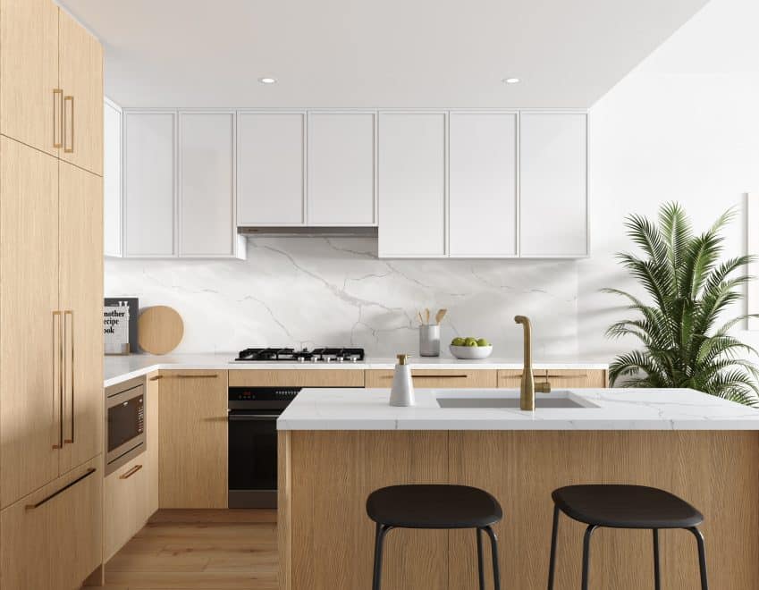 Florin – Light wood kitchen with an island, black stools, white cabinetry above, marble backsplash, and a potted palm plant beside the counter.