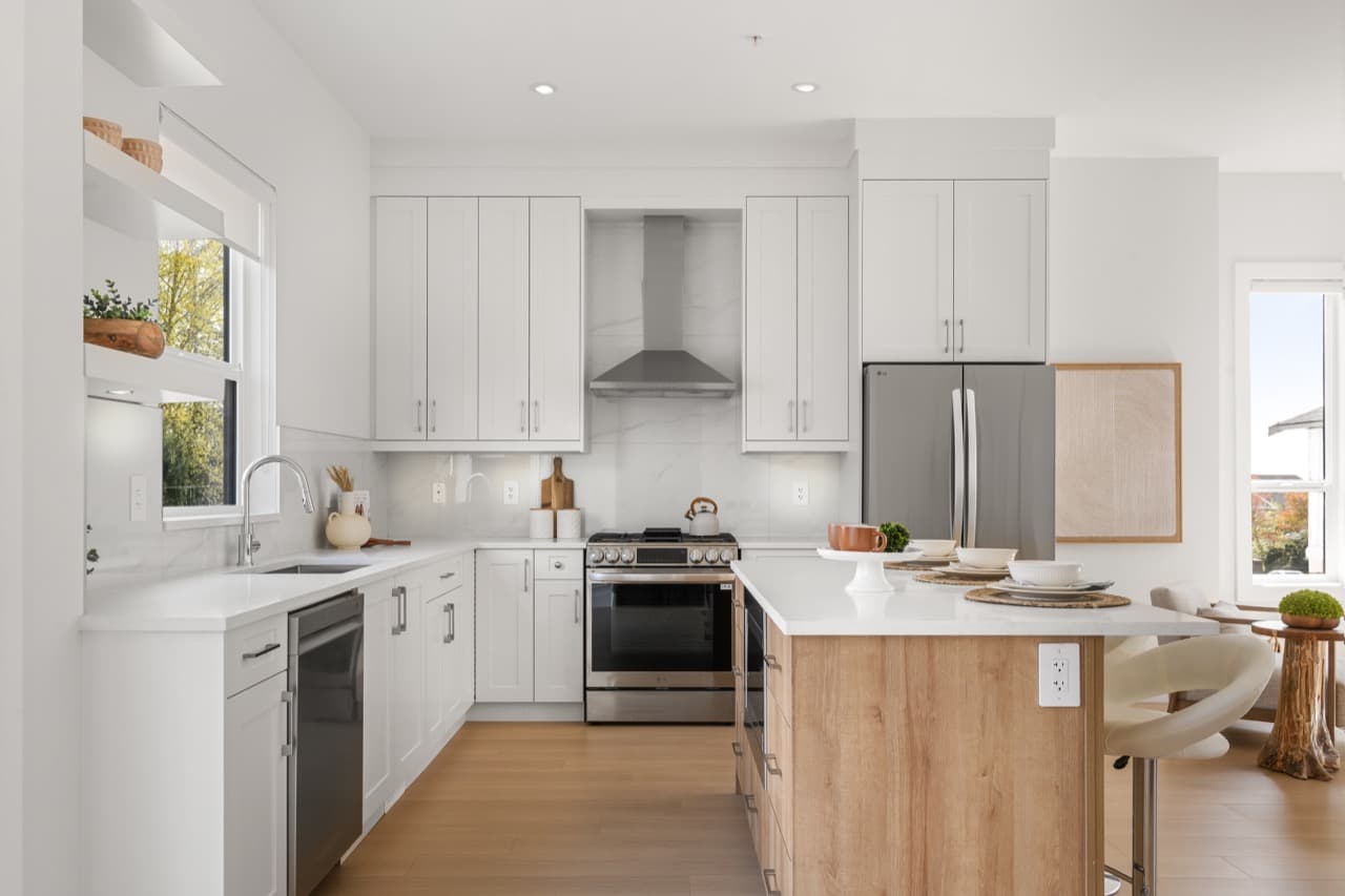 Gordon Square – Kitchen with white shaker cabinets, a marble-look backsplash and stove alcove, stainless range and fridge, and a wood-tone island.