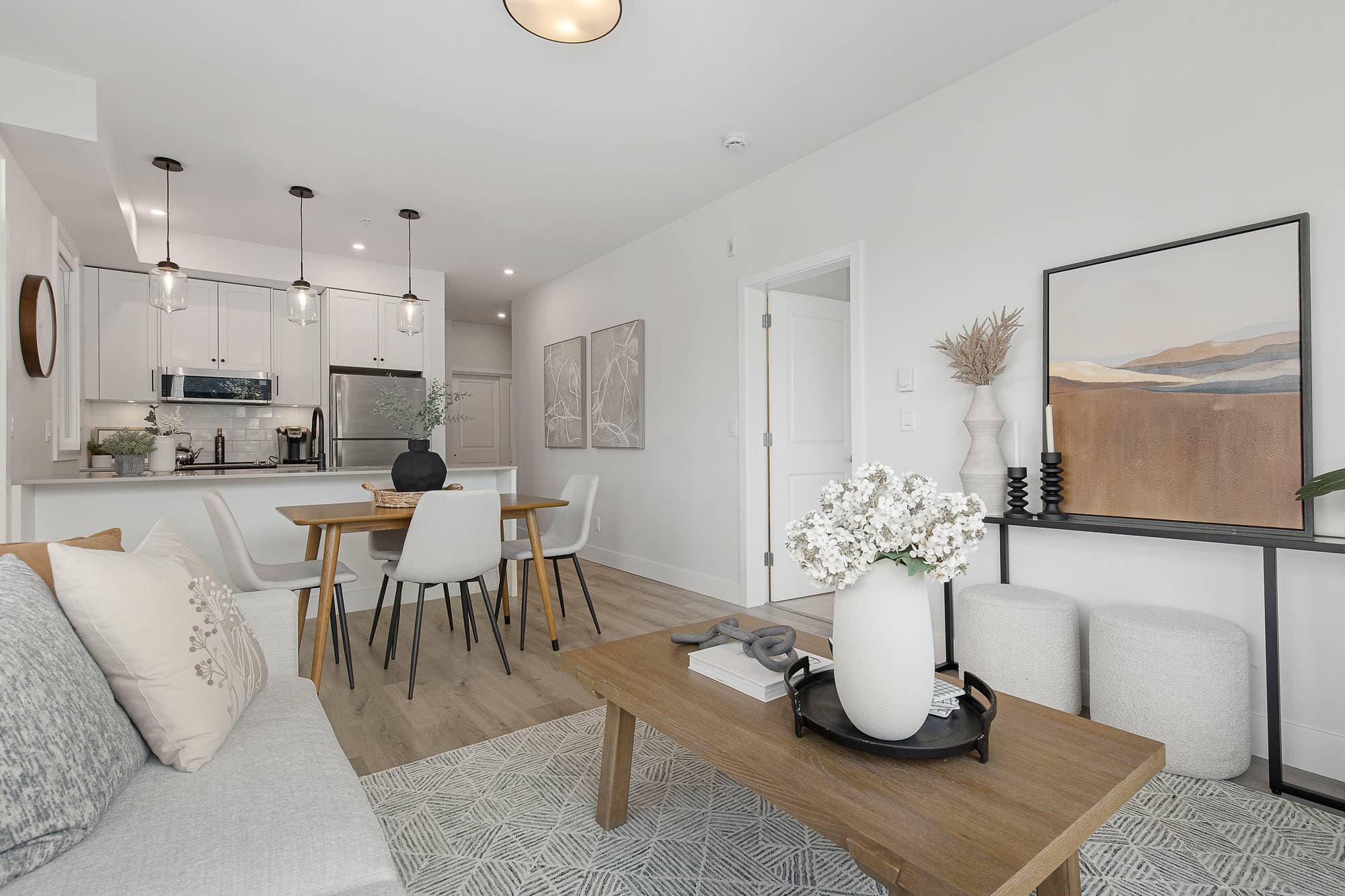 The Yearling – Open kitchen, dining, and living space with pendant lighting, a small dining table, and console with artwork.