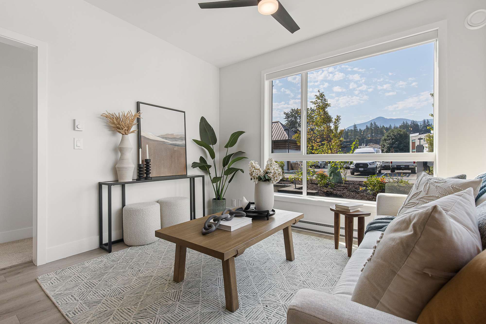The Yearling – Living room corner with a large window showing a mountain and treed view, sofa, and decorative console table.