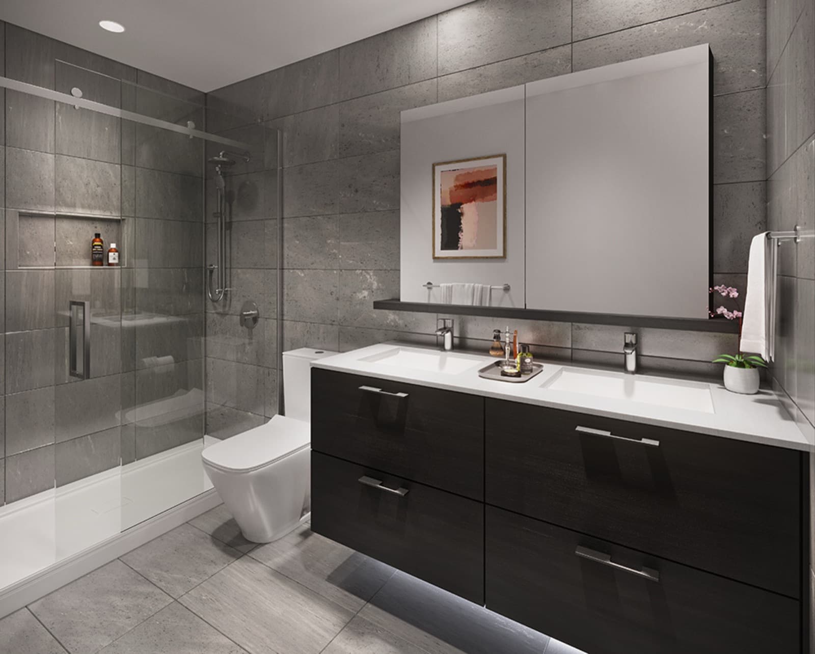 Akimbo Condos – A bathroom with a dark wood double vanity, framed abstract art, a large mirror, and a glass-enclosed shower with tiled walls.