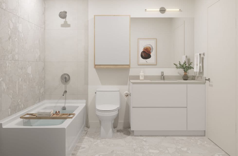 Marlow – A bathroom with a soaking tub, marble-look tile, a toilet, and a floating vanity with mirror.