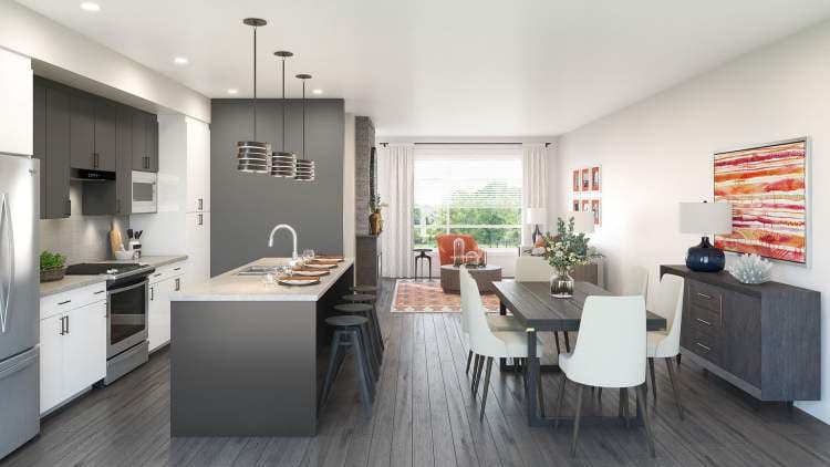 Base 10 – Open-concept kitchen and dining area with dark gray cabinetry, a center island, and a dining table with white chairs.
