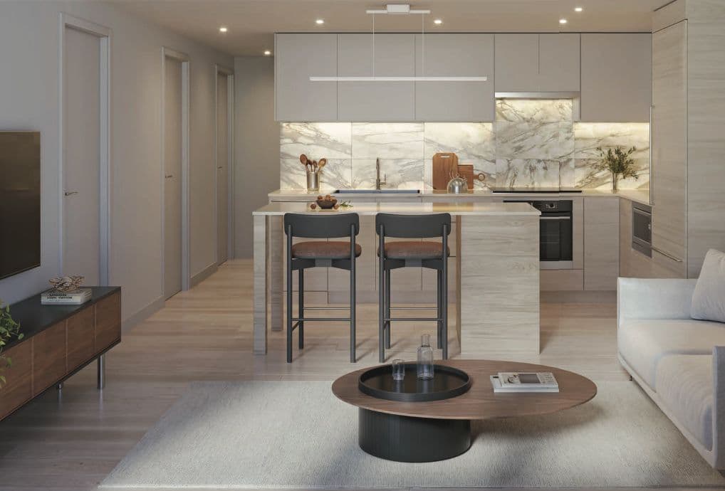 Juno Condos – Warm light-toned kitchen with a woodgrain island, charcoal bar stools, marble backsplash and a living area with a round walnut coffee table.