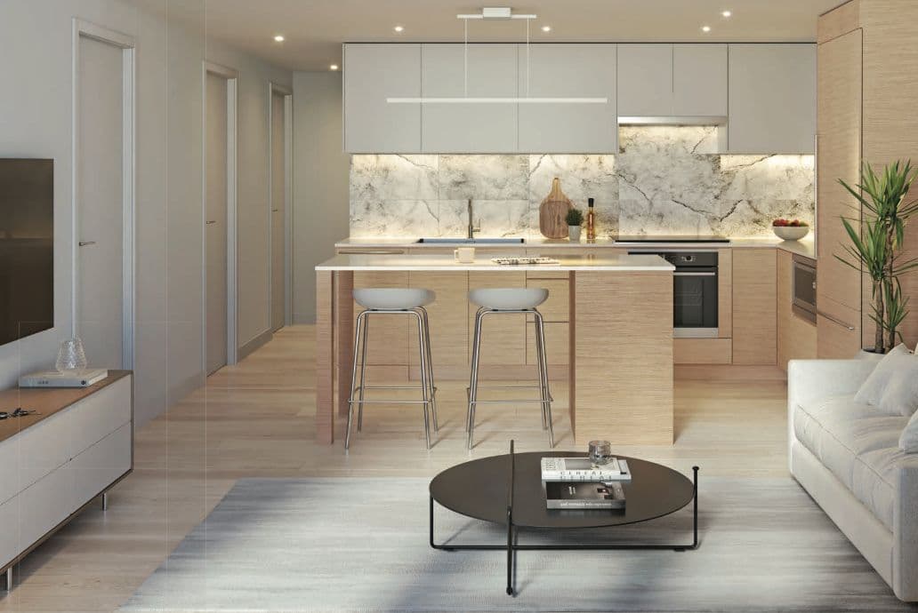 Juno Condos – Light-scheme kitchen and living space with a pale wood island, white counter stools, marble feature backsplash and a bright living area.
