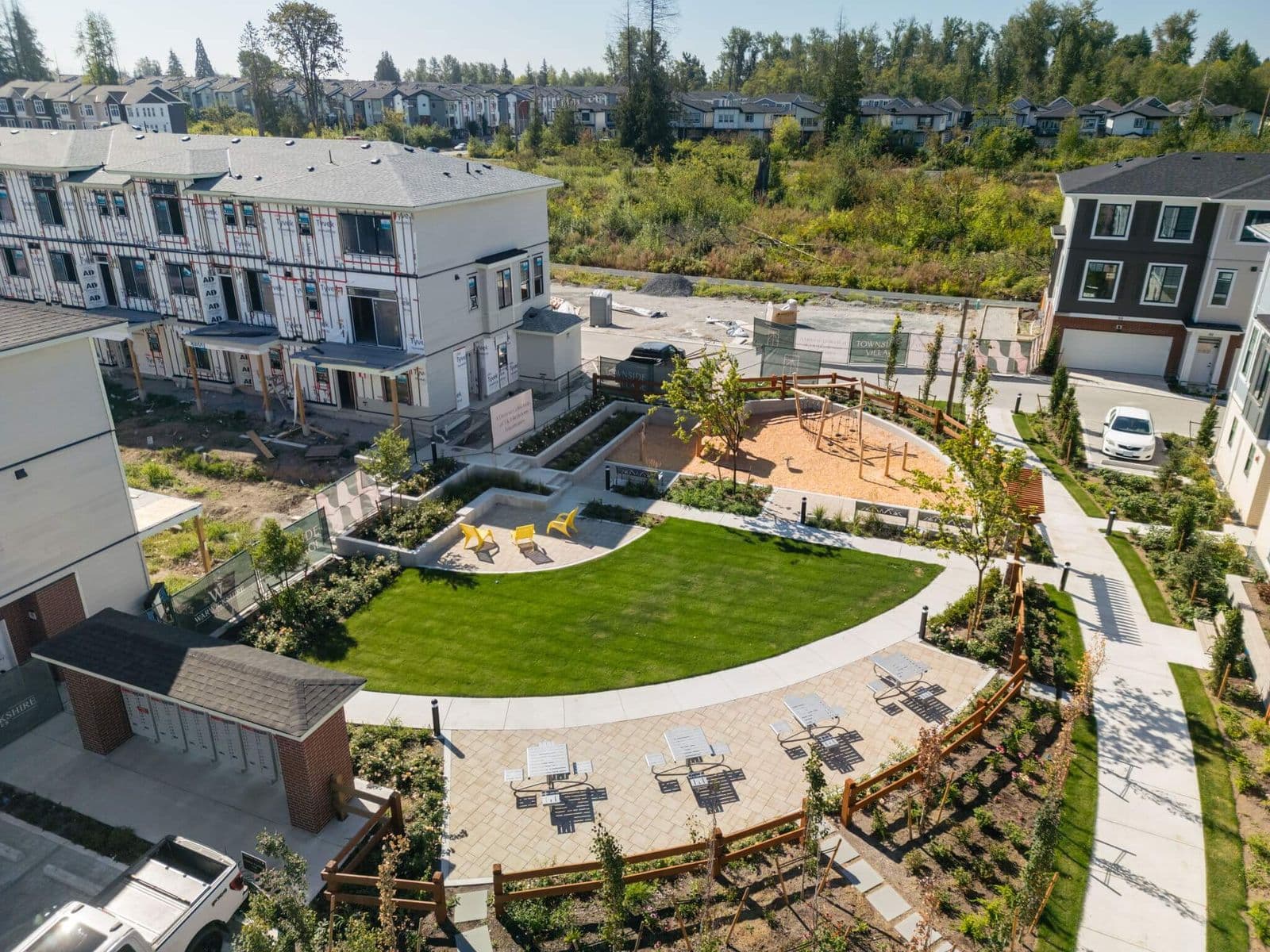 Townside Village – Aerial drone photo of the shared amenity space with playground, lawn, and seating, showing townhomes still under construction nearby.