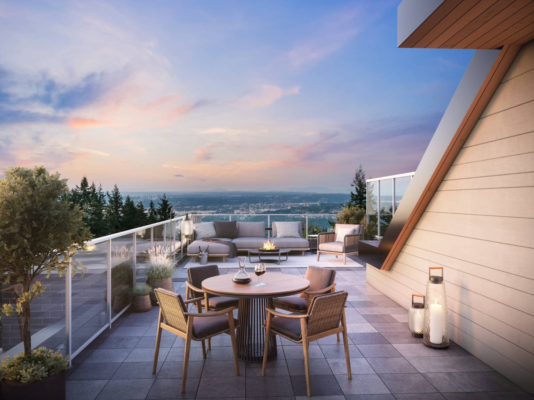 Arbour at SFU UniverCity – Rooftop terrace lounge and dining area at sunset with a fire pit table and lounge sofa, overlooking a distant hazy city skyline.