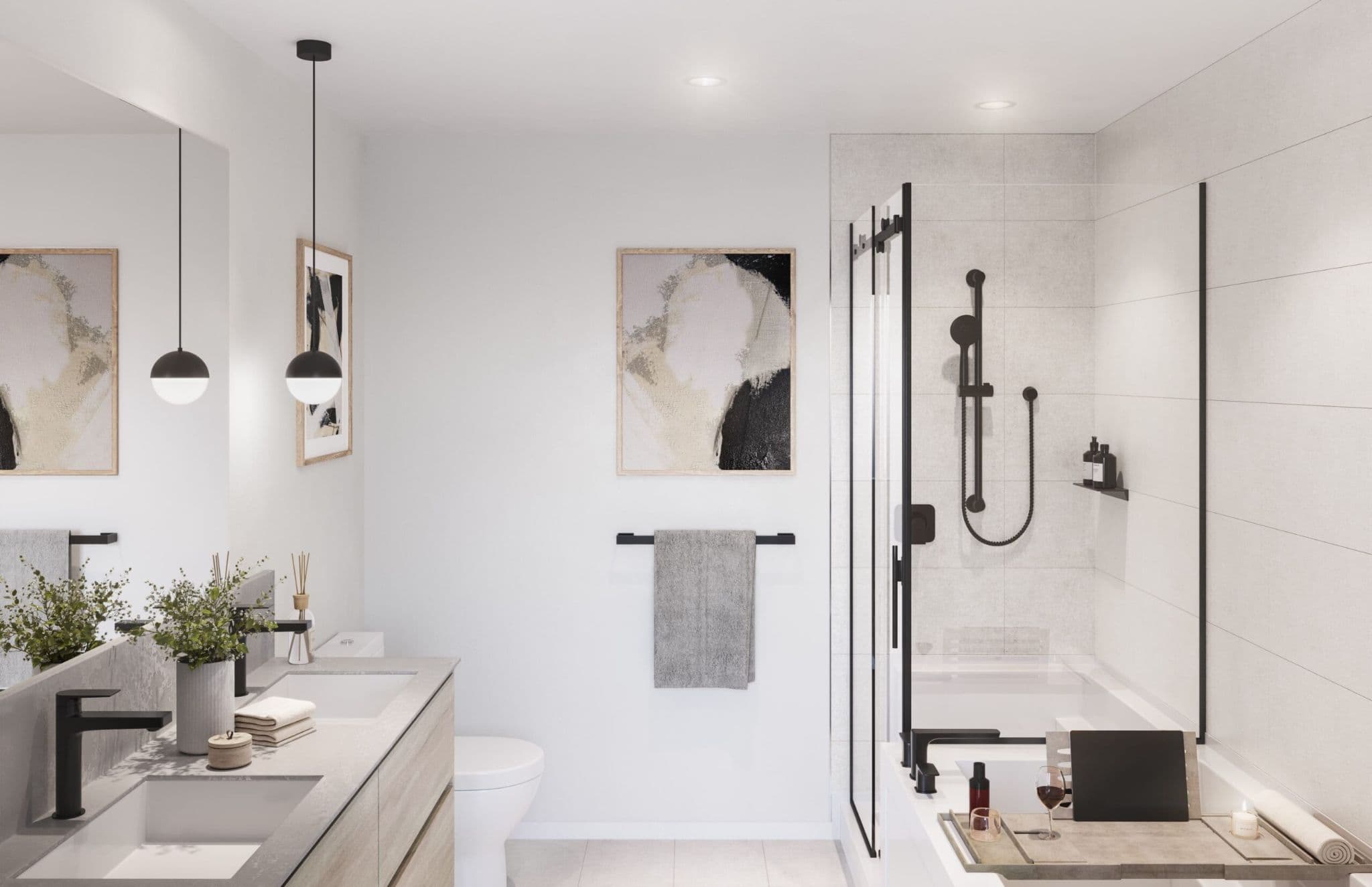 Arbour at SFU UniverCity – Bathroom with a stone double vanity, black pendant lights, framed artwork, and a soaker tub behind a glass shower panel.