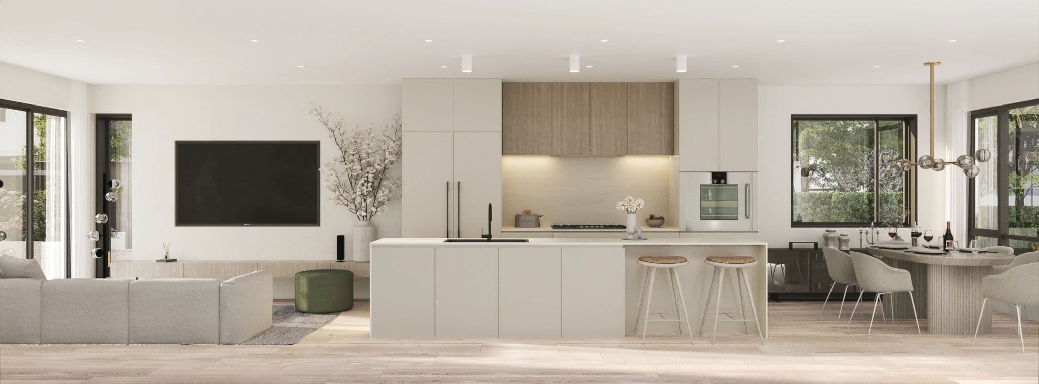 Emera – A spacious, open-plan modern living space featuring a central kitchen island with bar seating, light wood cabinets, and integrated appliances. The adjacent living area includes a wall-mounted TV and sectional sofa, while a light-filled dining space sits beside large windows on the right.