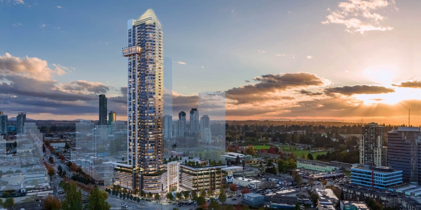 Whalley Station – Aerial dusk rendering of a very tall glass condo tower rising above a low-rise city with mountains and a park in the distance.