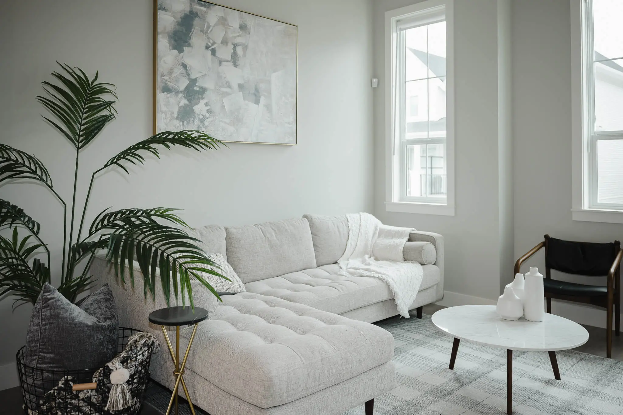Cedarbrook – The same beige sectional living room shown from another angle, with a round marble coffee table and a black accent chair.