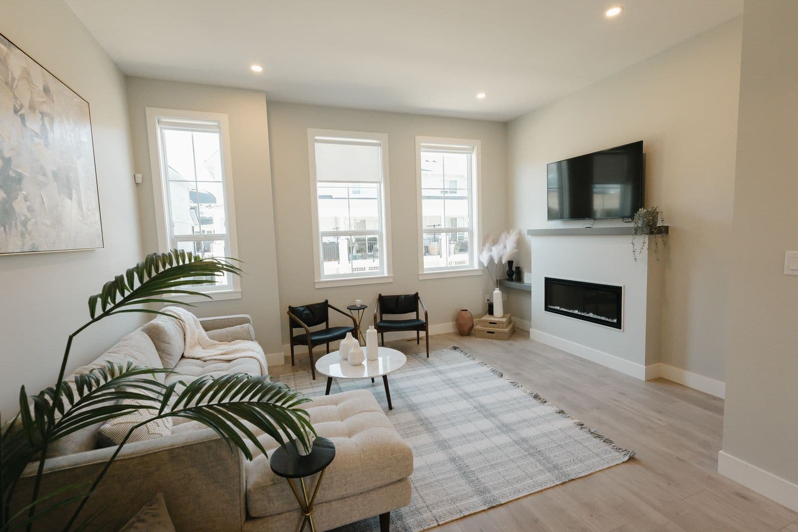 Cedarbrook – The same living room with the light grey sofa, fireplace, and mounted TV, viewed from a different angle.