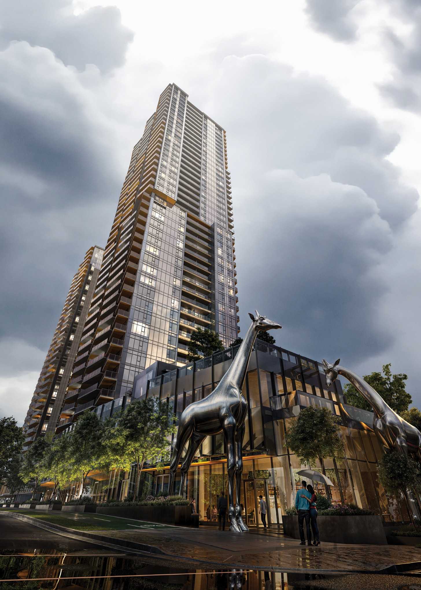 South Yards – Rendering looking up at a tall glass tower's retail podium from street level on a cloudy day, with large sculptural metal giraffe statues standing in front of the entrance.