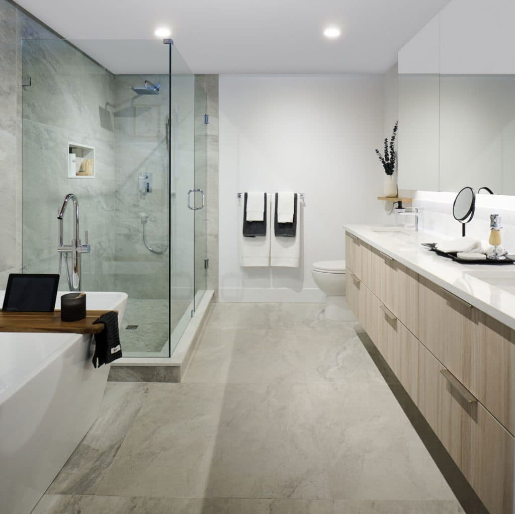 Executive on the Park – Bathroom with a freestanding tub, glass-enclosed shower, and a long wood double vanity with a large mirror.