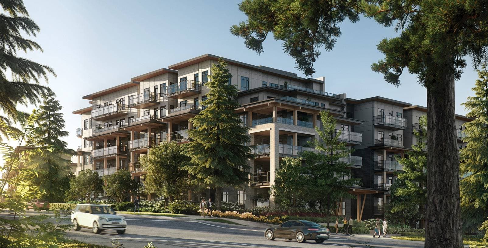 Baden Park – Street-level view of a modern multi-story condo building with wood-accented balconies, surrounded by tall pine trees, with cars and pedestrians on the road in front.