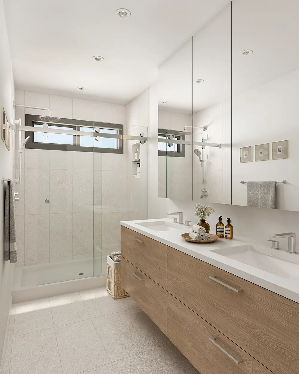 Lodana – A bathroom with a double vanity, wall mirror, glass-enclosed shower, and a small window.