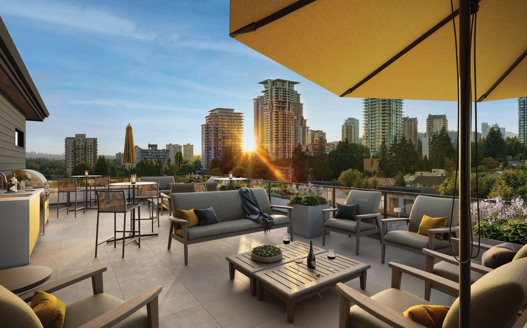 Lodana – A rooftop terrace with an outdoor kitchen, lounge seating under yellow umbrellas, and a view of high-rise towers at sunset.