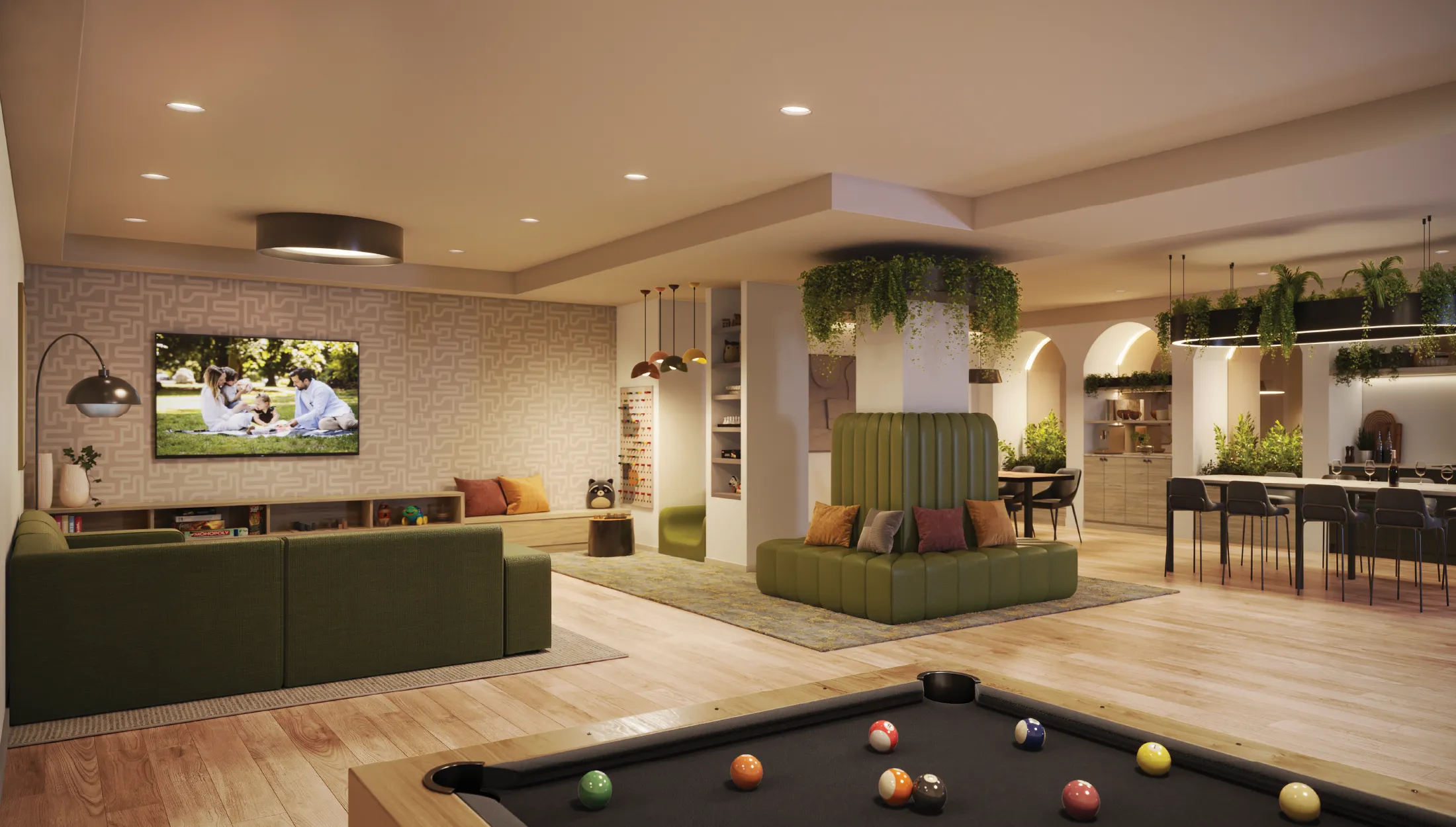 Lodana – A shared lounge and games room with green sofas, a wall-mounted TV, a pool table, hanging plants, and a communal dining area in the background.