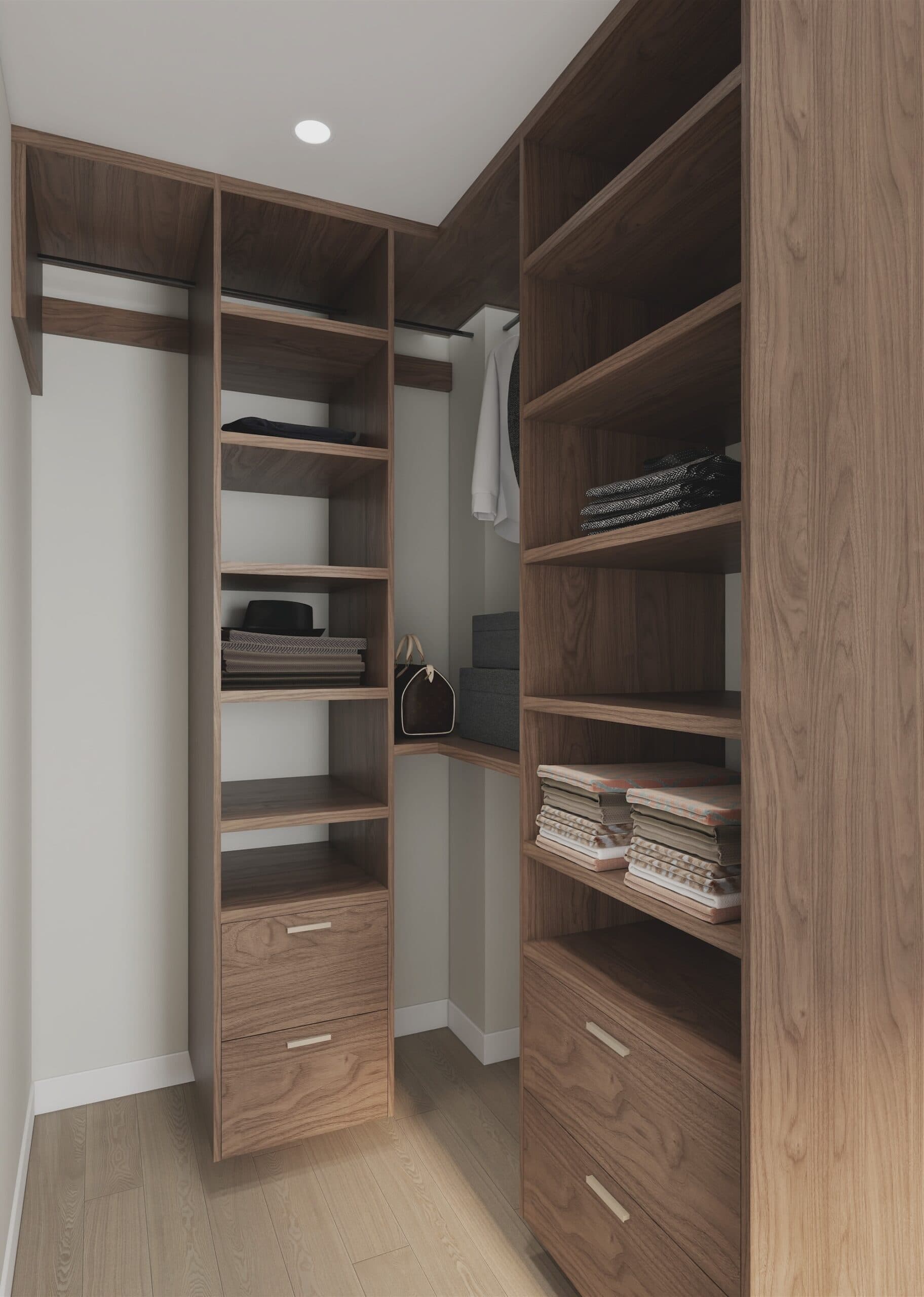 Kamilia – A modern walk-in closet featuring floor-to-ceiling built-in dark wood shelving and drawers over light hardwood flooring. The neatly organized space is softly lit by an overhead recessed light, displaying folded clothes, storage boxes, and a handbag on the shelves.