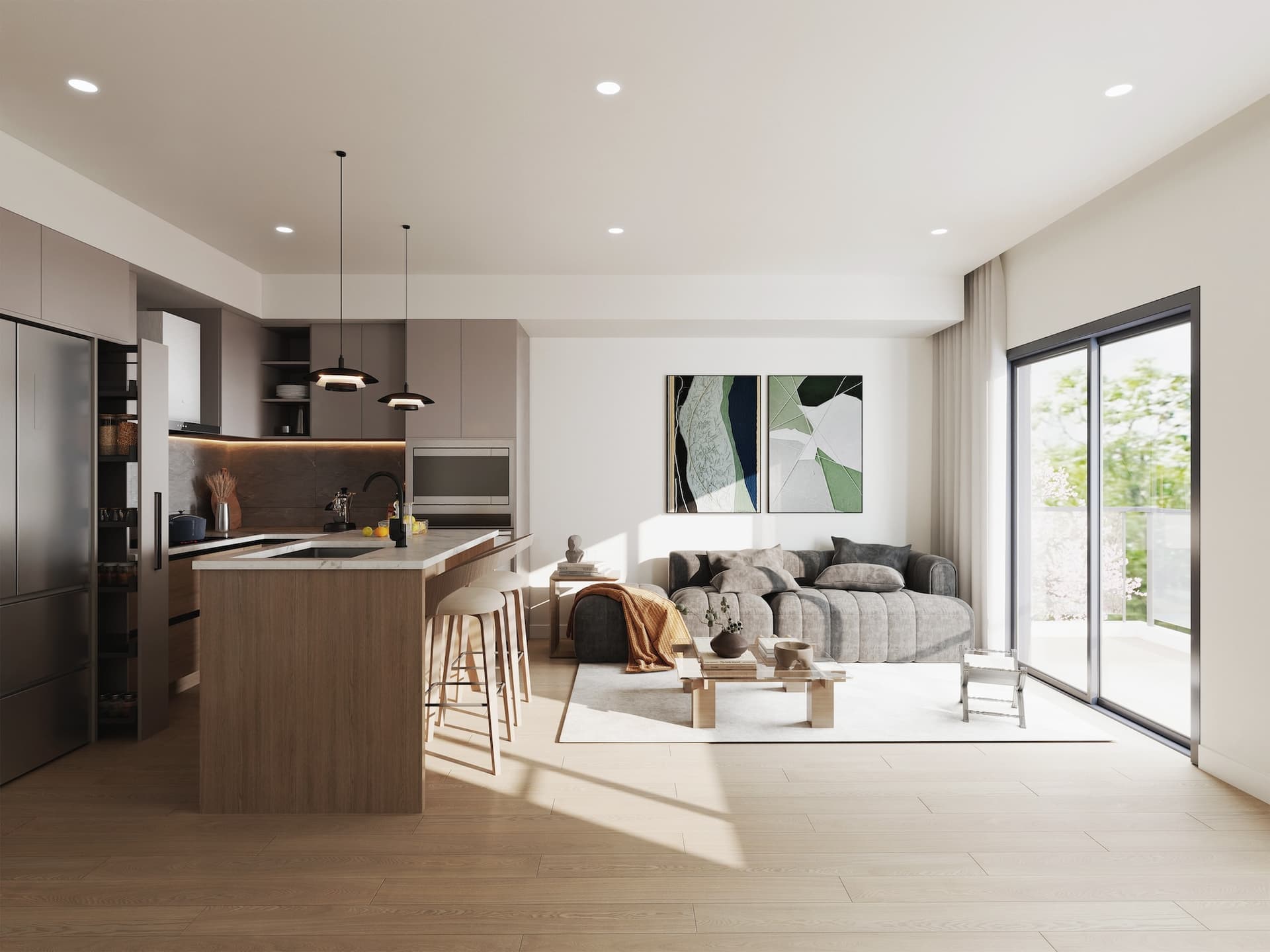 Kamilia – A bright, open-concept modern apartment featuring a kitchen island with barstools, muted taupe-gray cabinetry, and light wood flooring. The adjoining living area includes a low-profile gray sofa, abstract wall art, and large sliding glass doors leading out to a sunlit balcony.