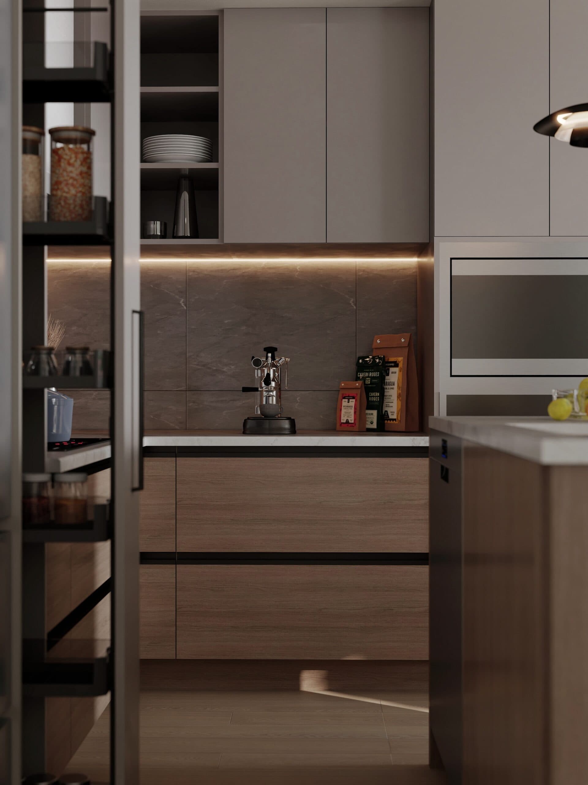 Kamilia – A contemporary kitchen scene showcases two-toned cabinetry with natural wood-grain lower drawers, matte gray upper cabinets, and warm under-cabinet strip lighting. A pull-out vertical pantry rack stands in the foreground, framing a marble countertop arranged with an espresso machine and bags of coffee.