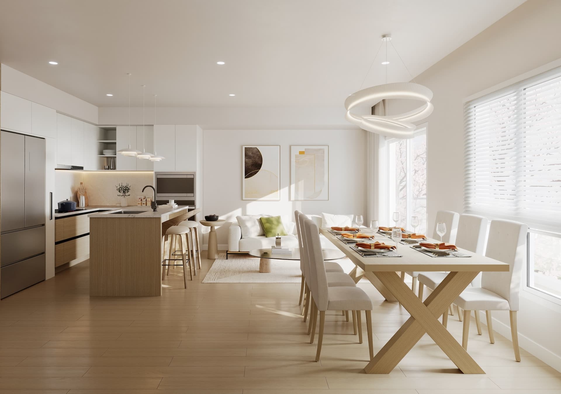 Kamilia – A bright, open-concept living space features light wood flooring, a modern kitchen with pale wood and white flat-panel cabinetry, and an island with bar seating. In the foreground, a light-wood dining table with an X-shaped trestle base is set for dinner under a sculptural looping pendant light, all washed in abundant natural light from large windows.