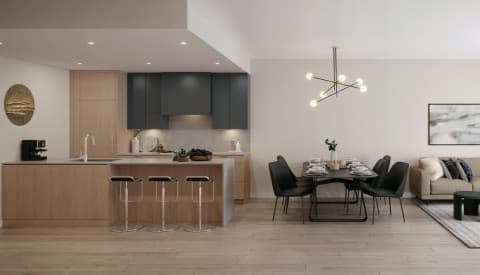Burqville – An open-concept kitchen and dining area with dark blue upper cabinets, a light wood island with bar stools, a round black dining table with black chairs, and a sofa in the background.