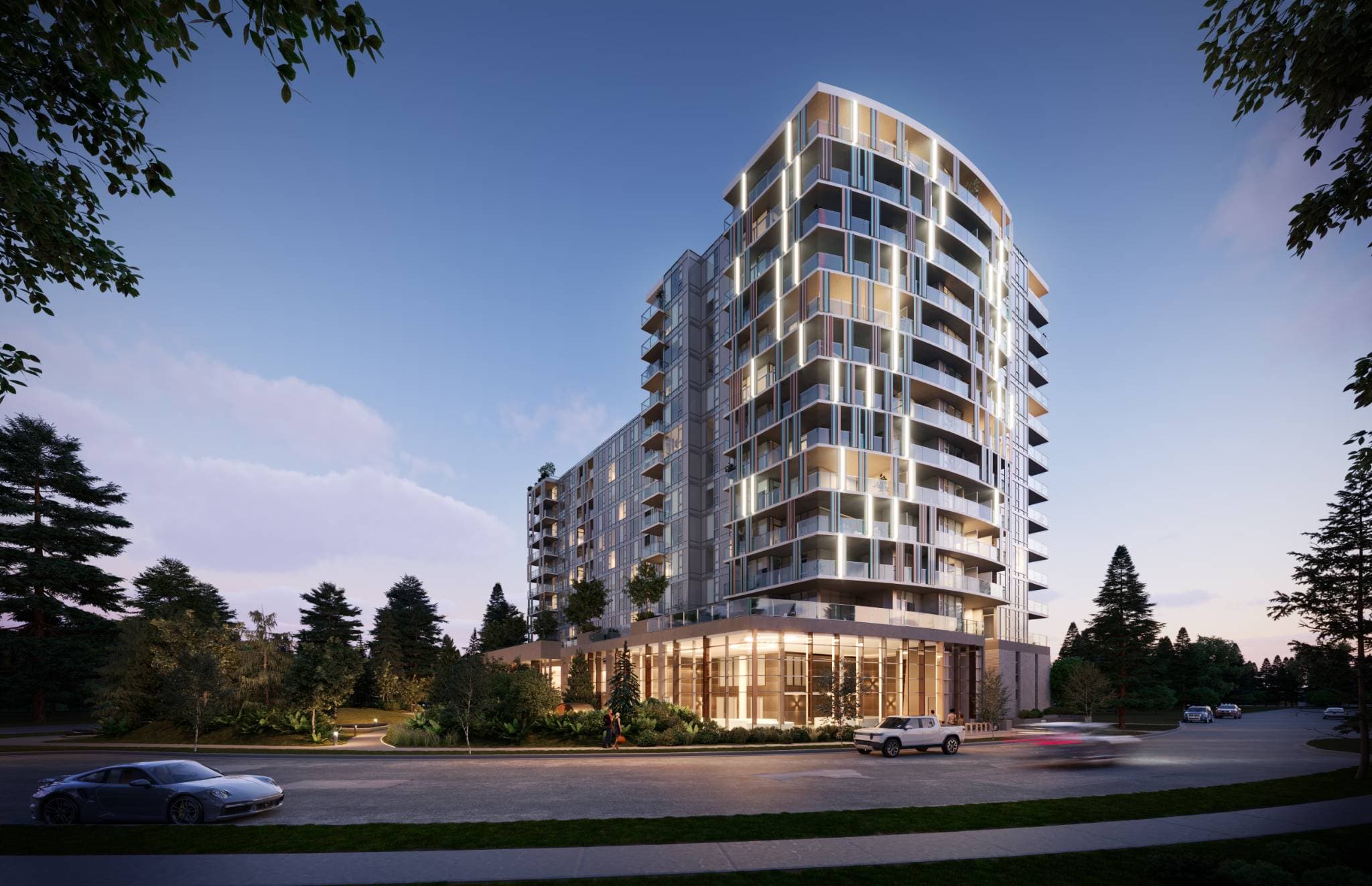 Talistar – A modern mid-rise residential building features glass balconies with integrated vertical strip lighting and a glass-walled ground floor lobby at dusk. The exterior shot captures the curved facade set along a quiet paved street framed by evergreen trees and landscaped walkways, creating a sleek, inviting ambiance.