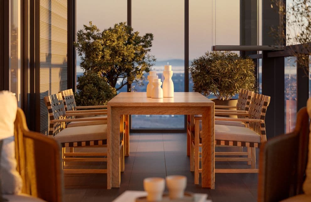 Solhouse 6035 – A high-rise terrace dining setup features a light wood table surrounded by woven-back chairs, decorated with sculptural white vases. Floor-to-ceiling glass railings reveal potted green shrubs and a panoramic city and mountain vista illuminated by warm dusk sunlight.
