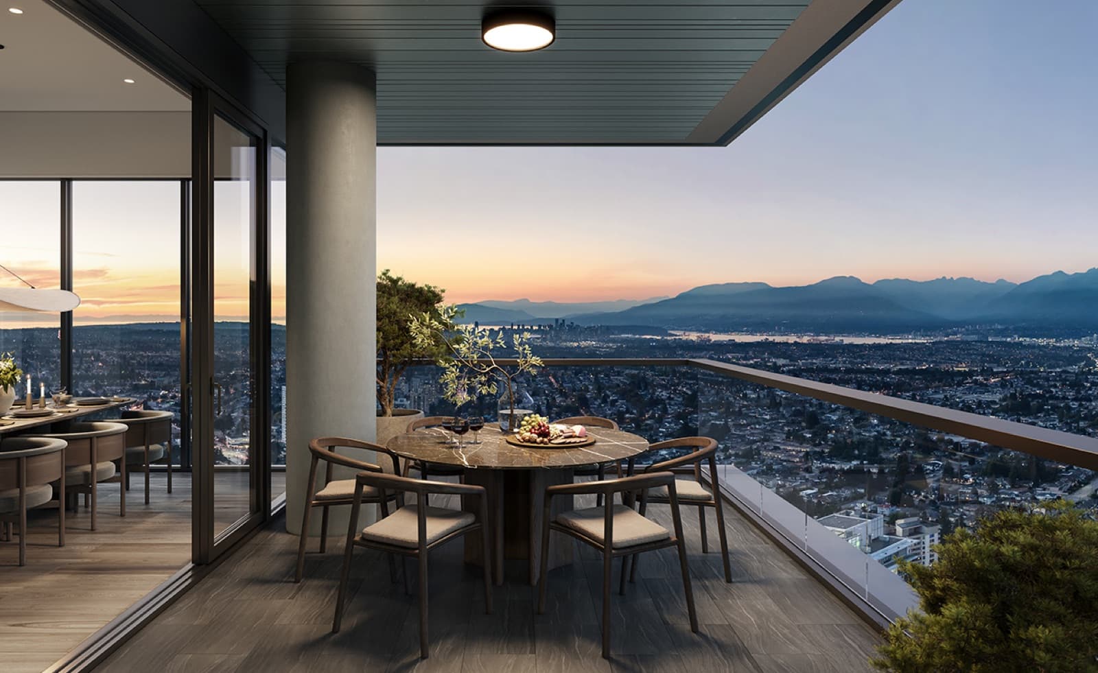 Solhouse 6035 – Private high-floor balcony with a round dining table and wine set out, overlooking the city, harbor, and mountains at sunset.