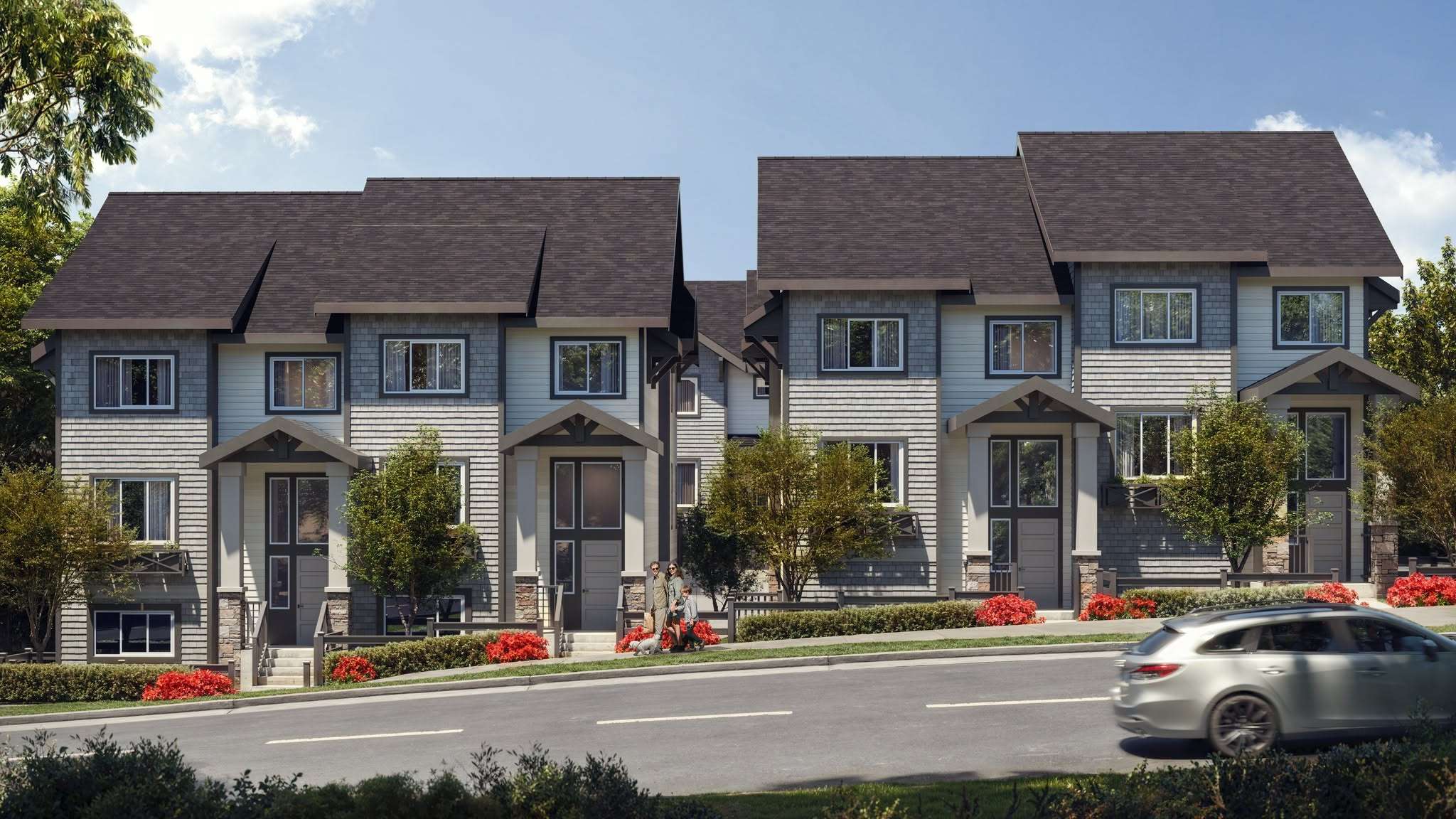 Hana – A row of two-story townhomes with gray shingle-style siding and covered porch entries, red flowering shrubs in front, a family and a car on the street.