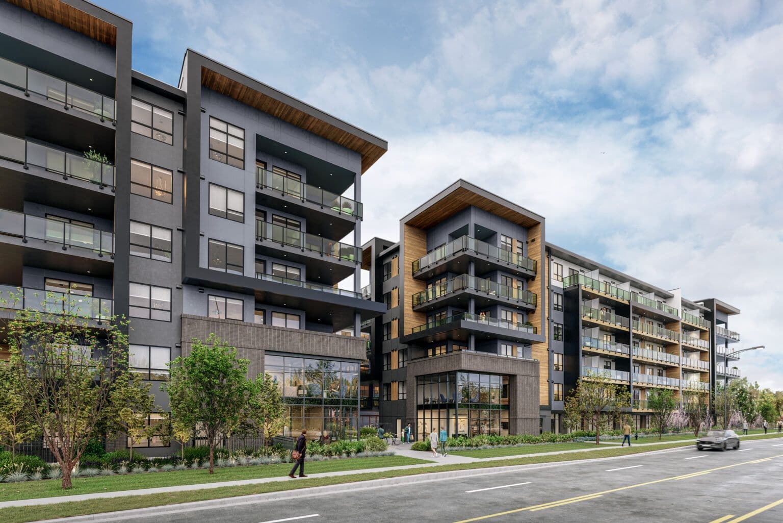 Scott + 77 – A modern mid-rise residential building features dark grey facades, warm wood-panelled soffits, glass balcony railings, and brick accents along the ground-floor storefronts. Pedestrians walk along a landscaped sidewalk with young trees and garden beds bordering a quiet paved street under a bright, soft blue sky.