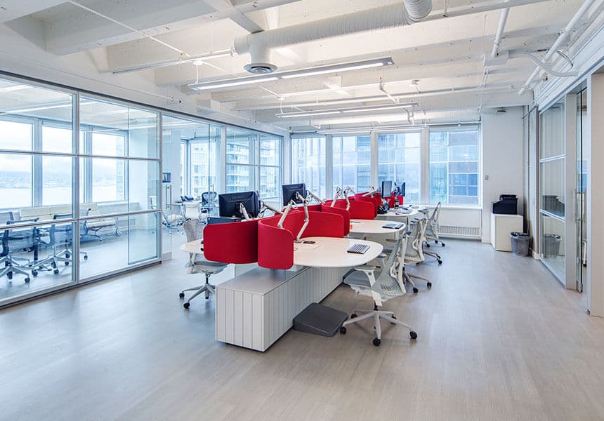 Crescentview at Edgemont – Bright open-plan office space with rows of desks, red-backed chairs, and floor-to-ceiling windows overlooking the city and water.