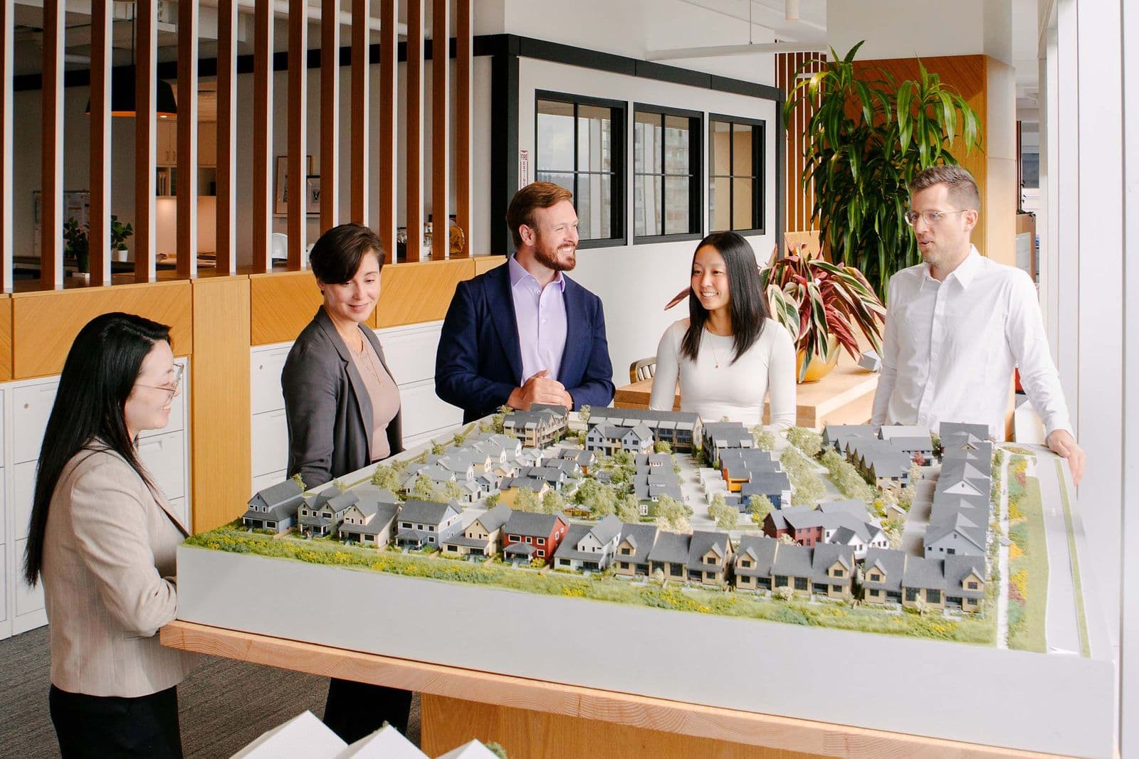 Mackin Parkside – A group of five people in an office looking at a large architectural scale model of townhomes and mid-rise buildings.