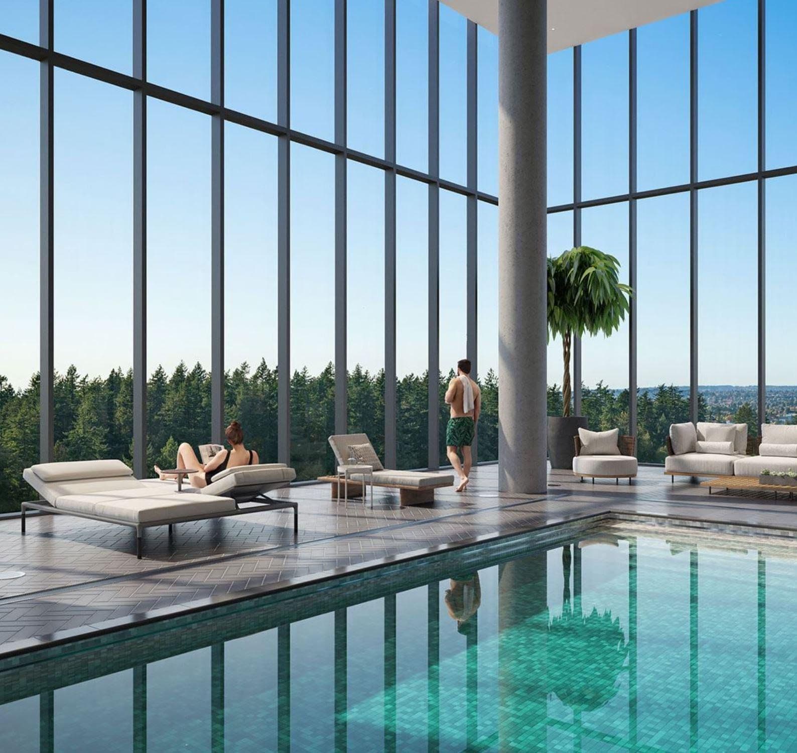 Central Park House – A bright indoor swimming pool lounge featuring double-height floor-to-ceiling glass windows that look out over a dense green forest landscape. People in swimwear relax on modern lounger chairs and sofas along the tiled pool deck under a clear blue sky.