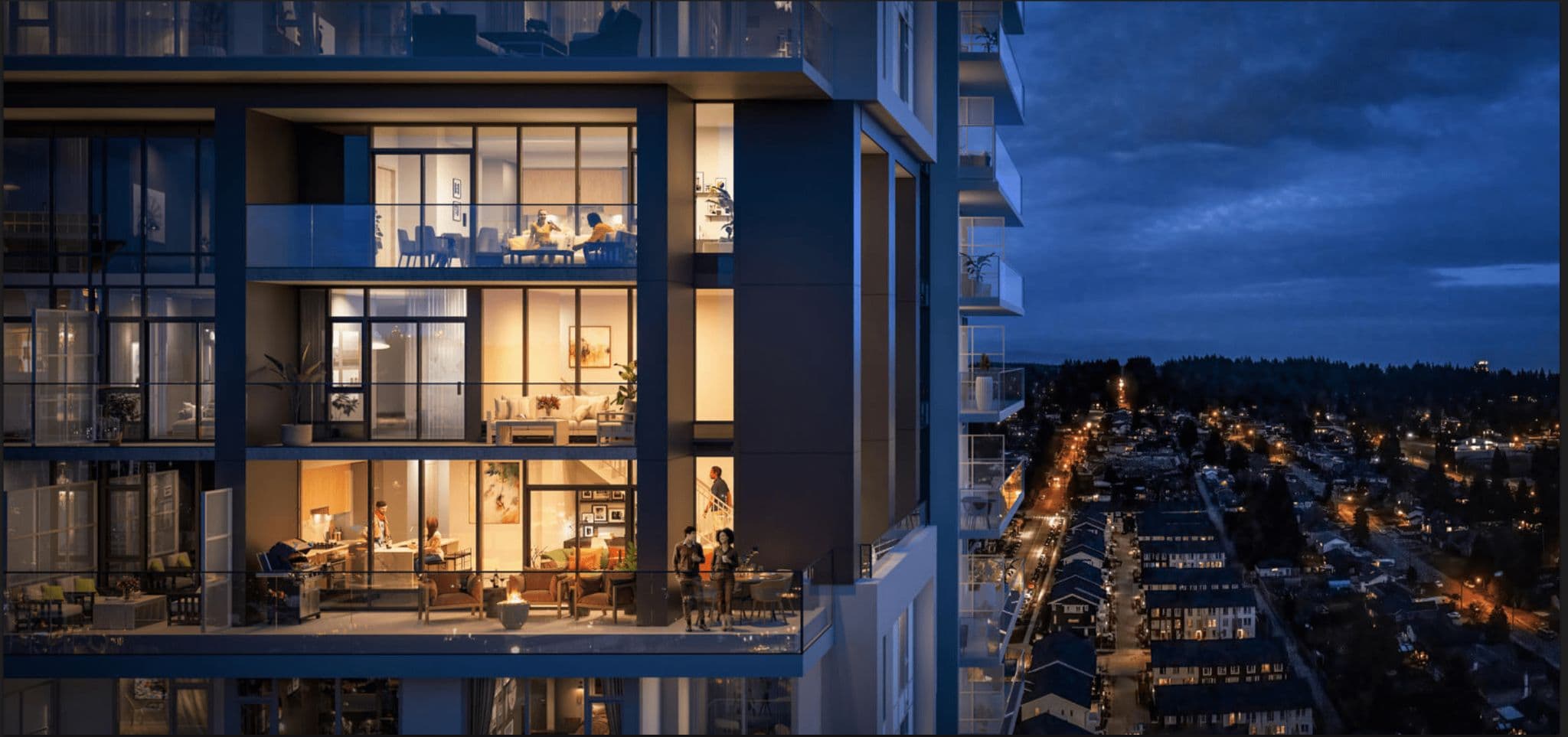 Vue – A twilight close-up of a modern residential high-rise facade showing multiple levels of floor-to-ceiling glass windows and illuminated suites. People are visible relaxing inside furnished living rooms and standing on a spacious balcony equipped with outdoor seating, overlooking a suburban neighbourhood and streetlights at dusk.