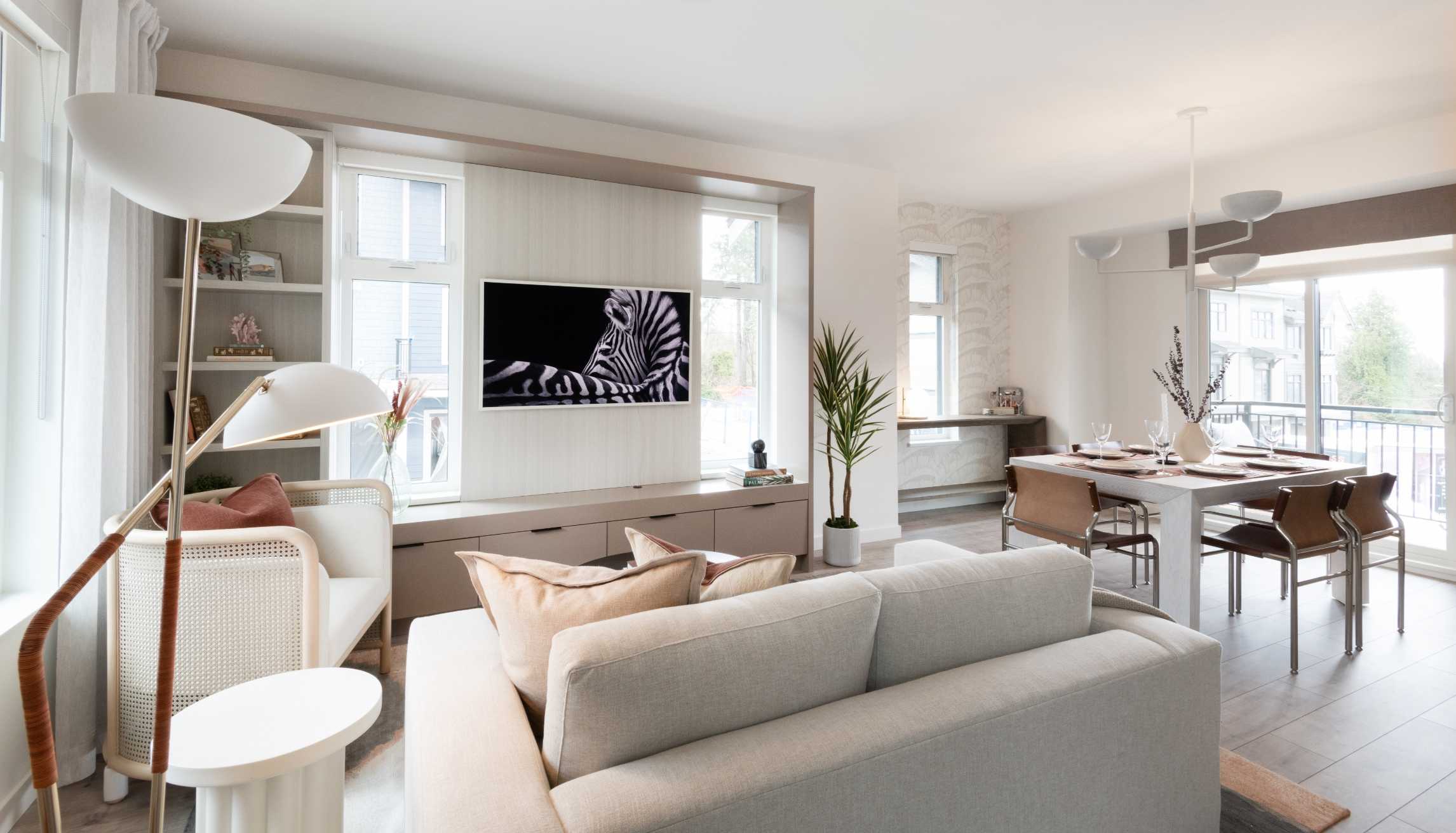 Cascadia – Open-concept living and dining area with a wall-mounted TV, built-in cabinetry, and a dining table set for four.