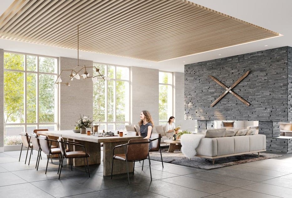 Parkside at Lynn – Shared lounge with a wood slat ceiling, stone feature wall with mounted skis, a dining table, and a sofa area where residents are seated near large windows to greenery.