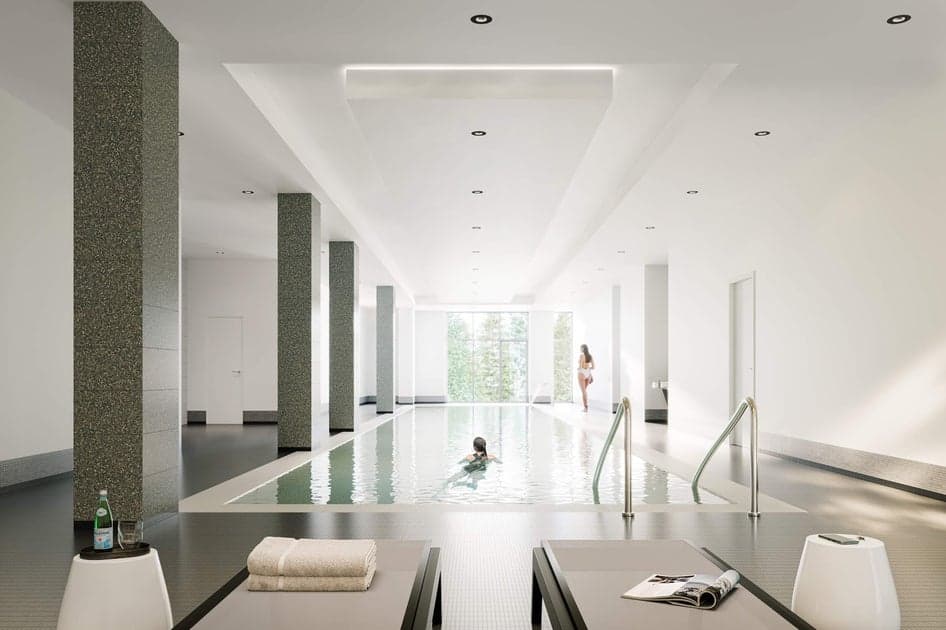 Parkside at Lynn – Indoor swimming pool with stone columns, loungers with folded towels, and a woman walking poolside while another swims.
