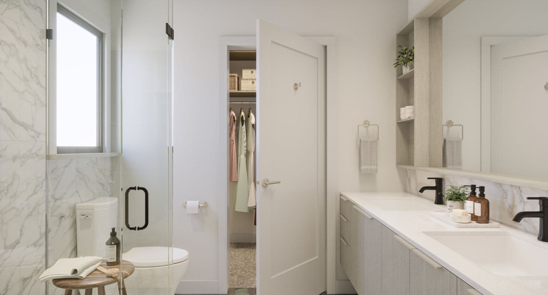 Amson Bloc – A modern, bright ensuite bathroom featuring a light wood double vanity with matte black faucets, marble-patterned tile, and a glass-enclosed shower next to a window. An open door reveals a carpeted walk-in closet with clothes hanging neatly inside.