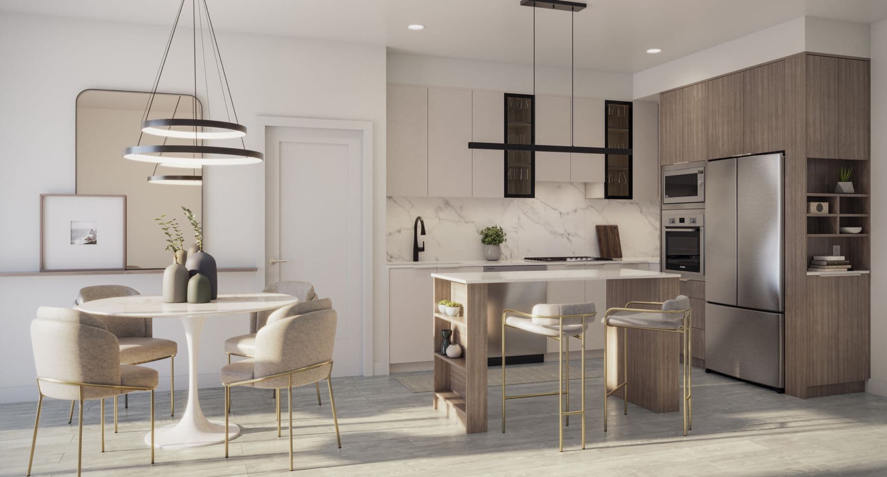 Amson Bloc – A modern open-concept kitchen and dining area features two-tone white and wood cabinetry, marble-style countertops and backsplashes, and integrated stainless steel appliances. In the foreground, a round tulip dining table with upholstered brass-legged chairs sits beside a compact kitchen island with matching barstools under contemporary pendant lighting.