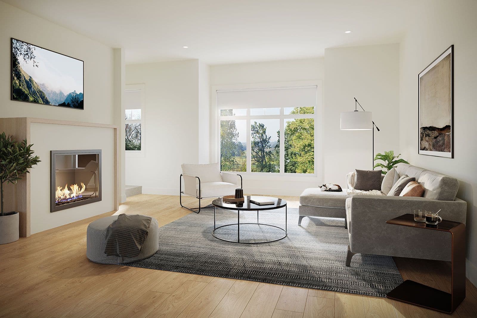 The Loop – Living room with a two-sided fireplace, wall-mounted TV, wood accent chair, grey sectional sofa, and a large window looking out to trees.