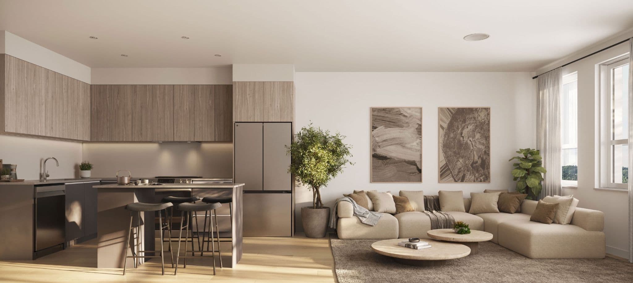 The Merchant – Open-concept kitchen and living area with wood cabinetry, a stainless fridge, bar stools, a beige sectional sofa, and framed abstract art on the wall.