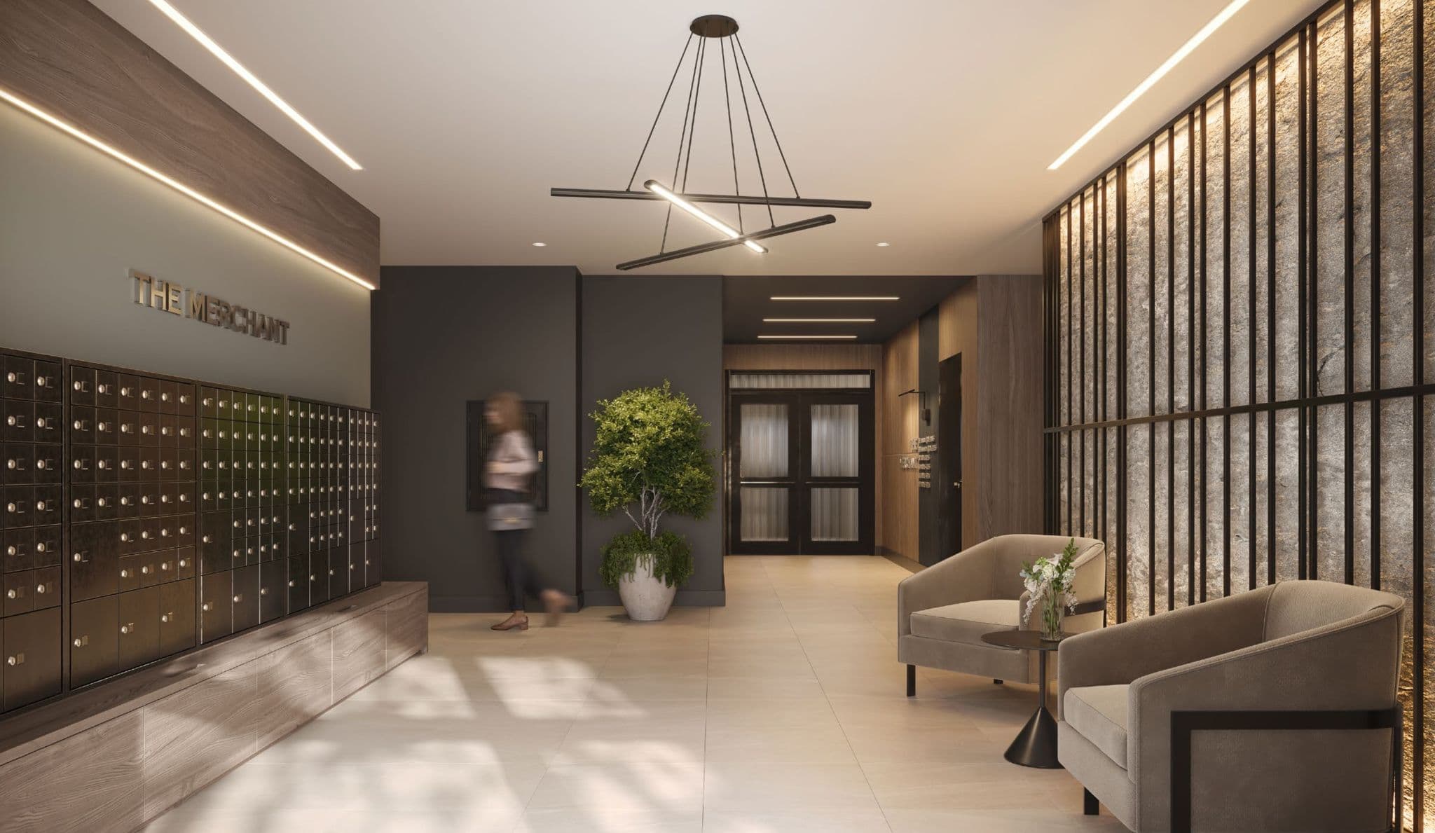 The Merchant – Building lobby with a wall of bronze parcel/mail lockers, a sign reading THE MERCHANT, a seating area with armchairs, and glass entry doors beyond.
