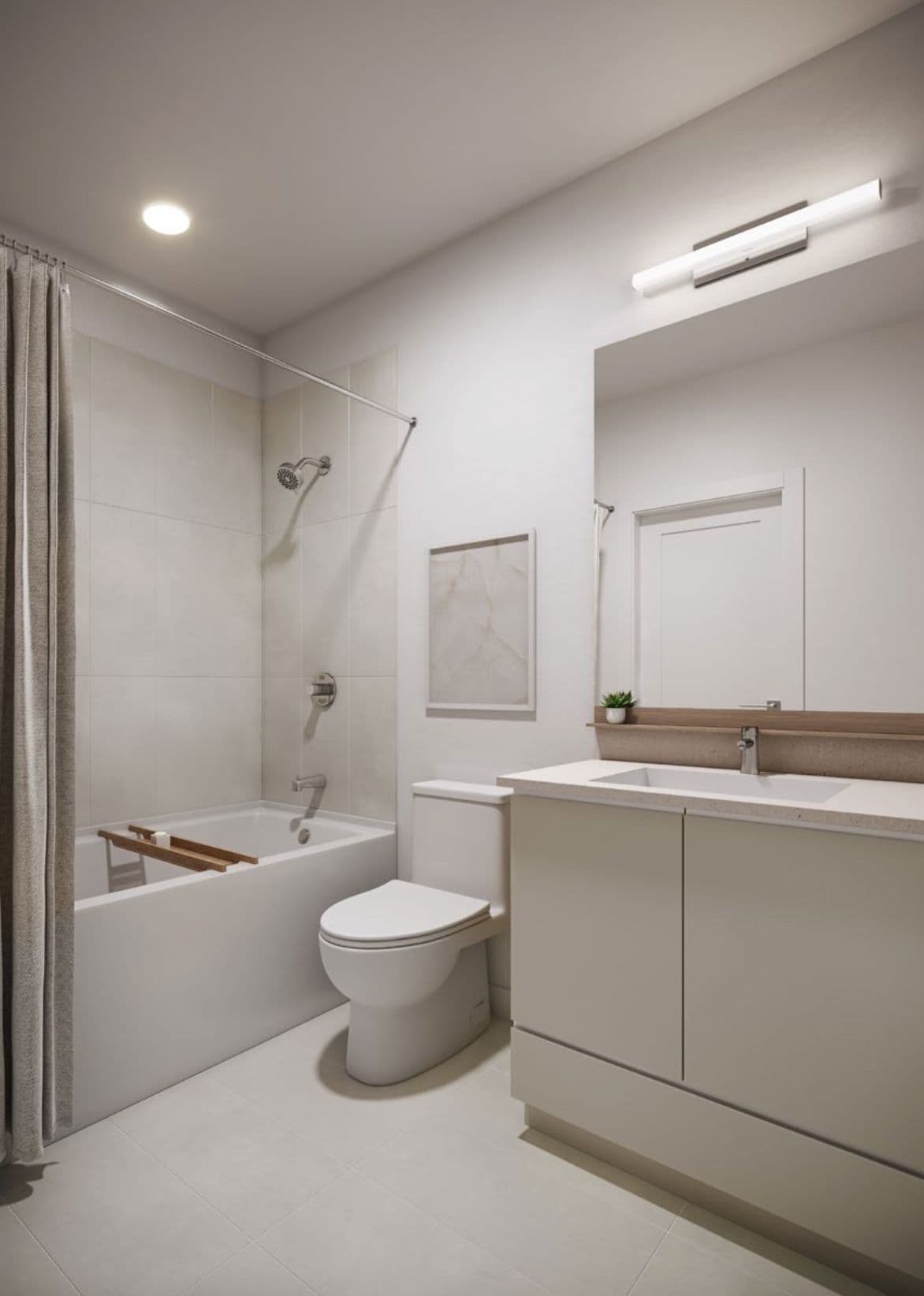 The Merchant – Bathroom with a tub/shower combo, toilet, and a light-toned vanity with a single sink beneath a large mirror.
