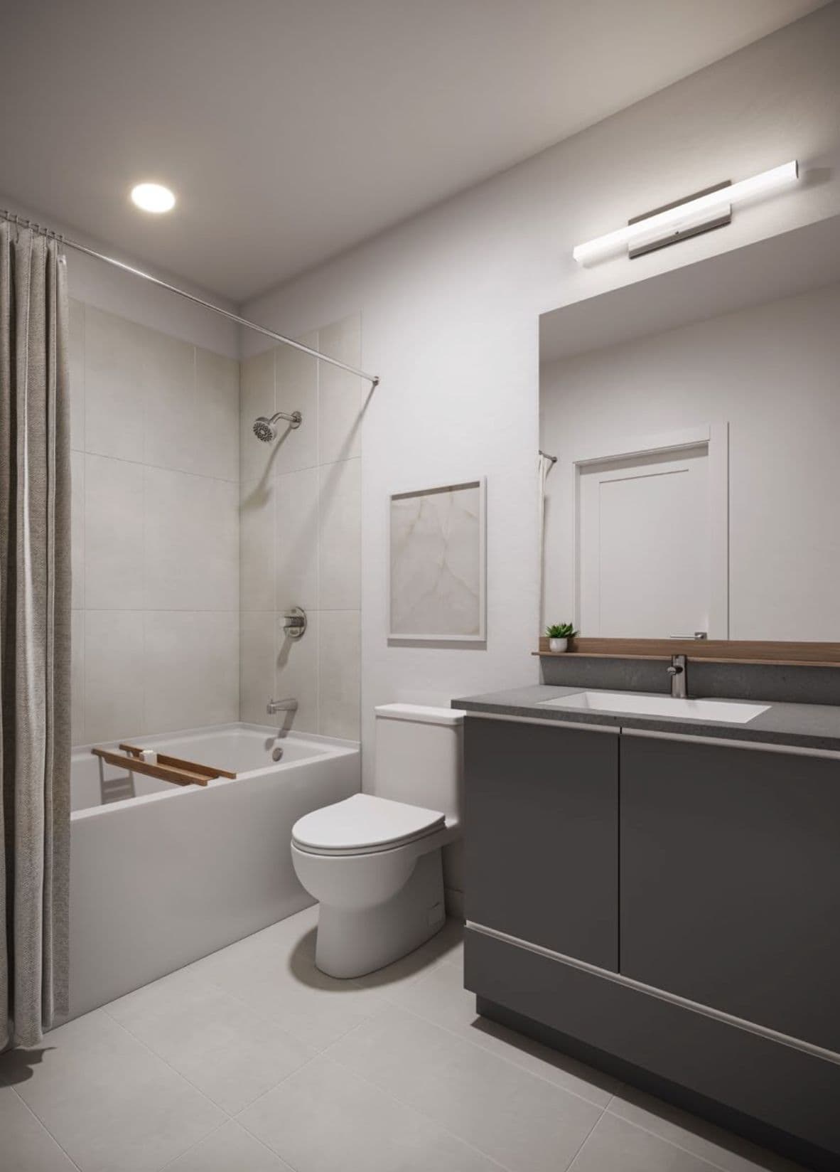 The Merchant – Bathroom with a soaker tub and shower curtain, a toilet, and a dark grey vanity with a single sink beneath a large mirror.