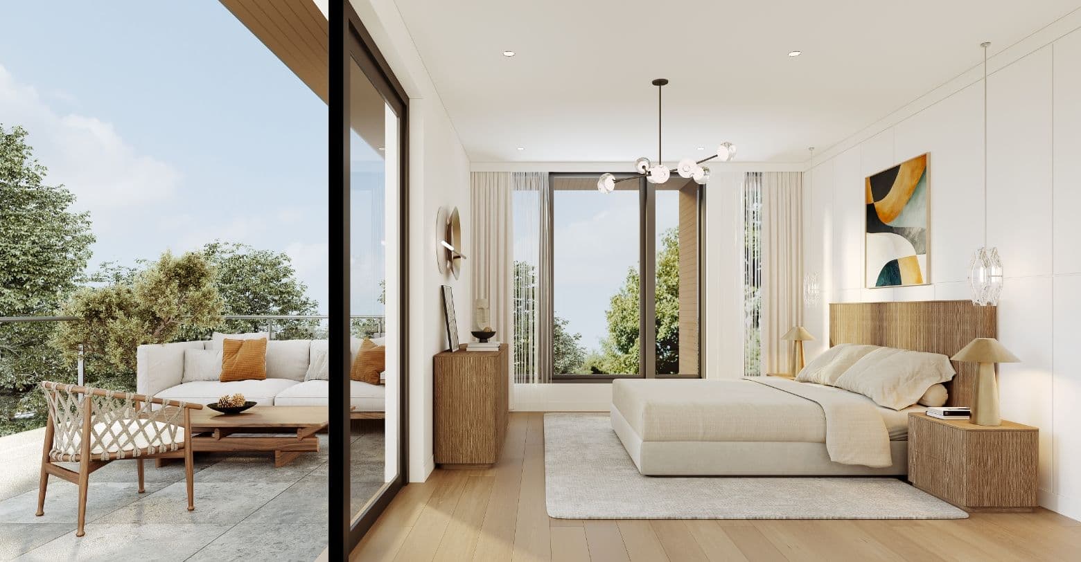 AderaWest – A bright, modern bedroom featuring light wood flooring, neutral linens, and fluted wood furniture that opens onto a spacious outdoor balcony lounge with comfortable seating. Floor-to-ceiling sliding glass doors and windows invite abundant natural daylight and frame peaceful views of surrounding lush green treetops under a clear sky.