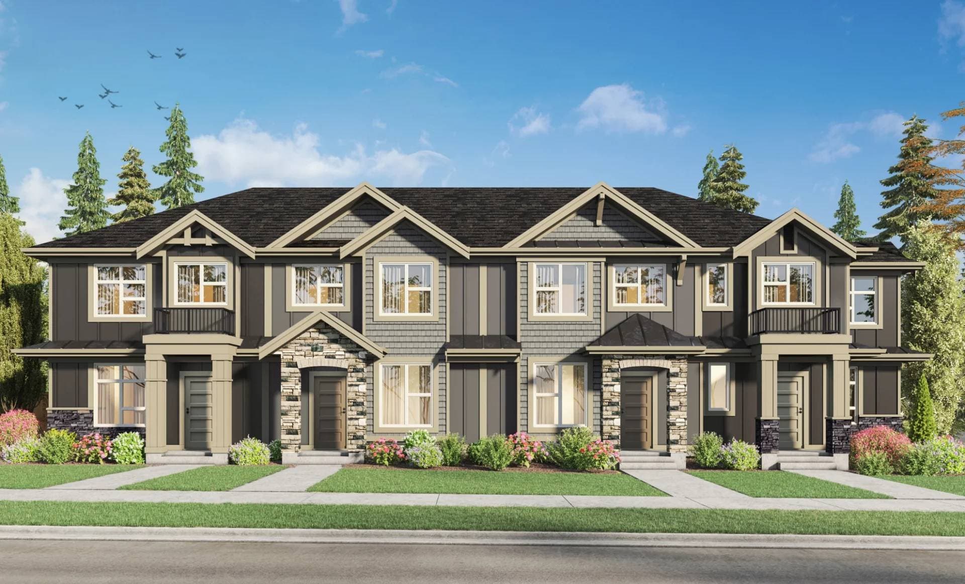 Brighton West – A ground-level rendering of a modern two-story townhome building featuring dark gray board-and-batten siding, light beige trim, and natural stone accents around the entryways. The front yard includes a neat green lawn with concrete walkways, manicured flower beds, and tall evergreen trees set against a bright, sunny sky.